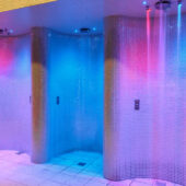 Curved experience showers with mosaic tiles and atmospheric lighting.