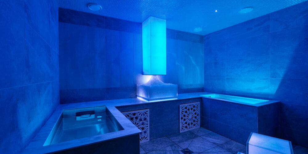 An ice experience room with an ice chute and blue cool lighting.