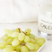 Caudalie treatment candle next to a bunch of grapes