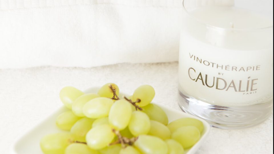 Caudalie treatment candle next to a bunch of grapes
