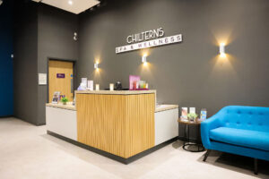 Reception desk at Chilterns Spa & Wellness with a blue sofa and wall lights.