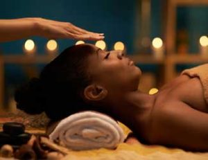 Lady receiving reiki treatment to improve energy flow in relaxing treatment room.