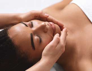 A lady in a relaxed position and environment receiving a facial treatment.