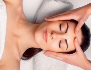 Lady receiving relaxing facial treatment from spa therapist