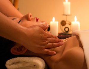 Lady relaxing with facial treatment, candles in the background.
