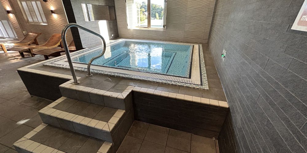 Moulton spa pool with steps to access and relaxation benches in the background.