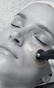 A lady with closed eyes relaxing and enjoying a facial treatment.